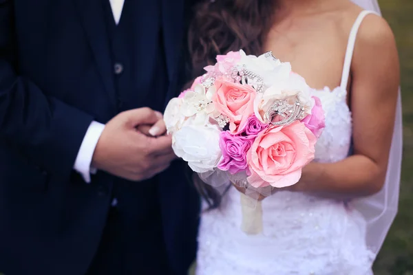 Bride and groom holding hands. Bride holding wedding paper flower bouquet