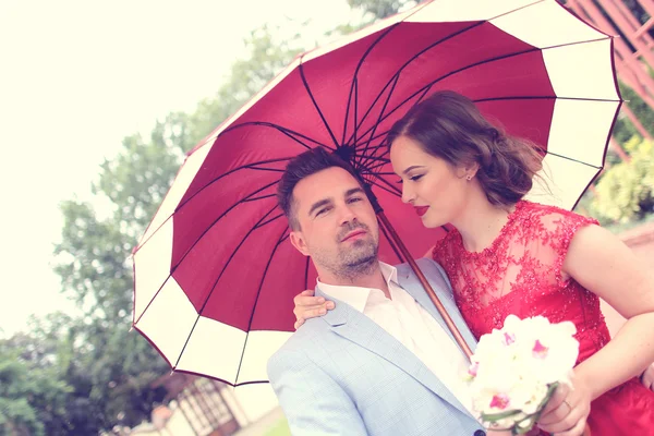Beautiful couple with red umbrella on a rainy day