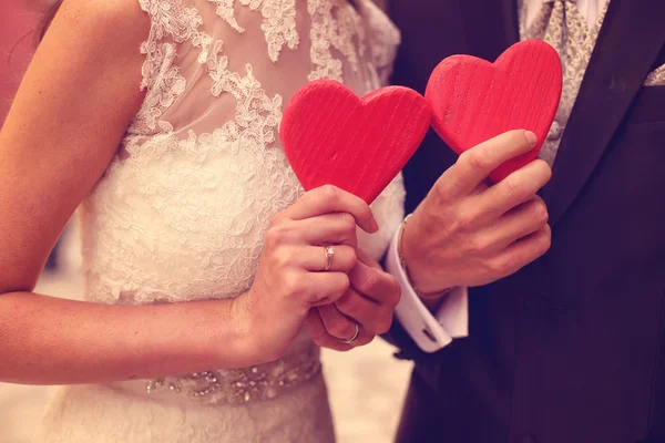 Bride and groom holding red hearts