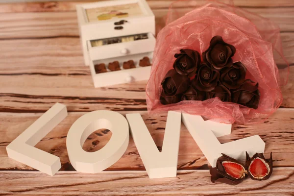 Mini chocolate sweets and LOVE letters on a wooden table