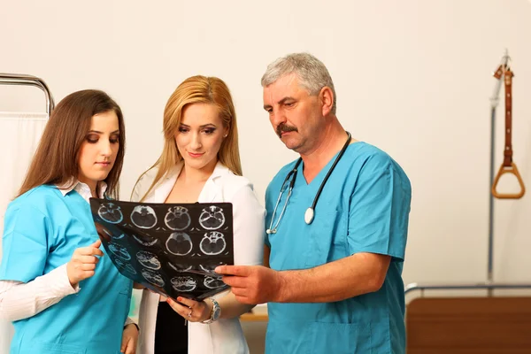 Mature male doctor with two female nurses checking on a radiography
