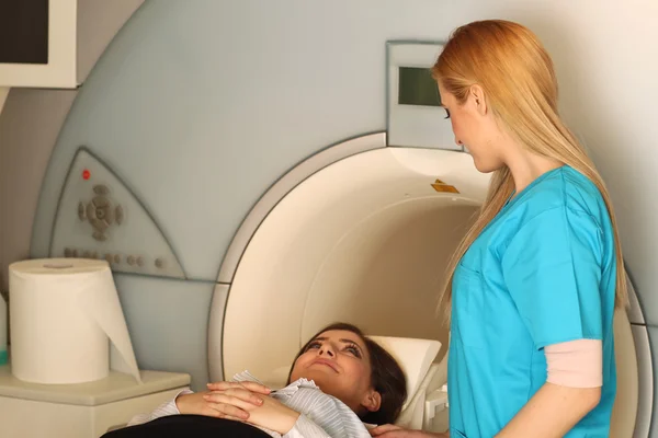 Radiologic technician next to her patient lying on a CT Scan bed