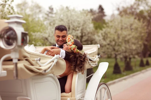 Bride and groom sitting in a white carriage