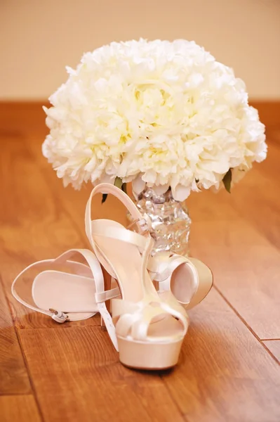 Beautiful wedding bouquet with bride's shoes on wooden floor