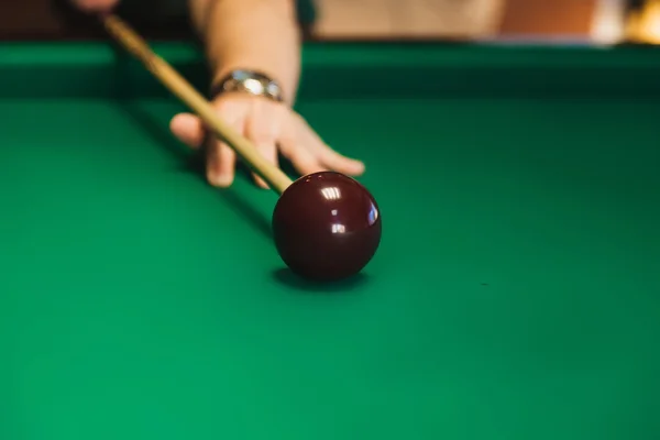 Details of the game of billiards. Red ball in the center of the frame. Player aiming cue in a billiard ball.