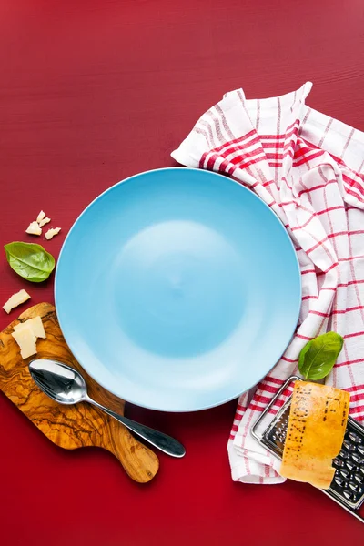Empty porcelain plate and kitchen towel on a bright background.