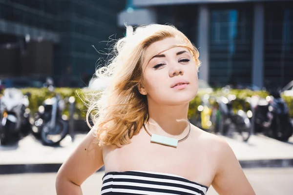 Beautiful young blonde girl posing on city street