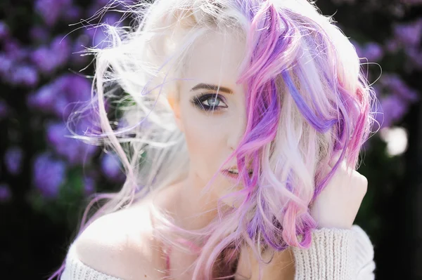 Blonde girl hipster with lilac and pink hair posing outdoors