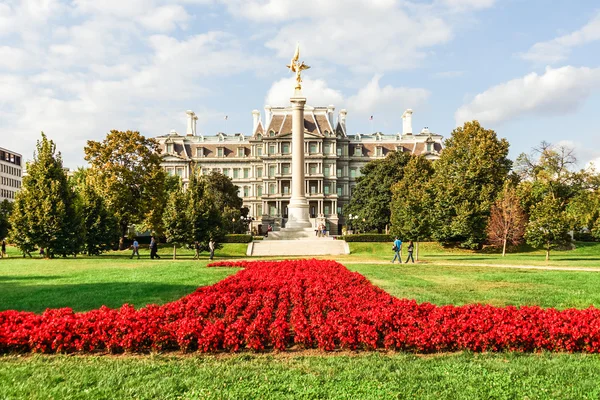 The Eisenhower Executive Office Building and First Division Memorial column with flower lawn in front on a bright and sunny fall day.