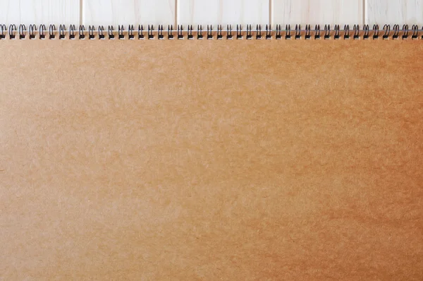 Empty blank brown front page cover of spiral bound notepad on the wooden background.