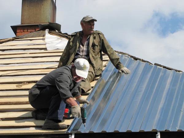 Two workers install roof