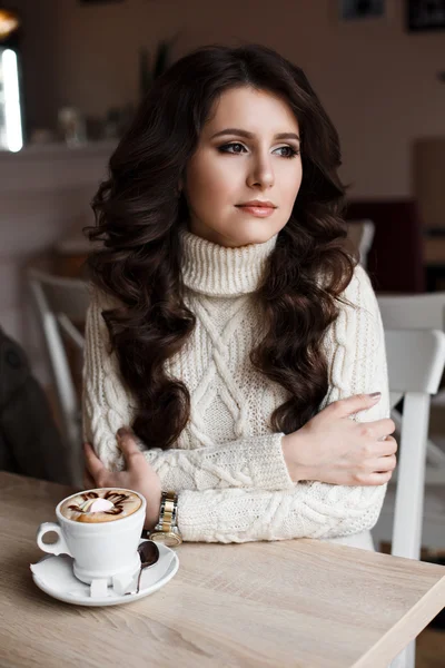 The girl with dark hair at a table in the restaurant. Waiting for my order of cocoa. Curly hair, beautiful makeup, expressive eyes.