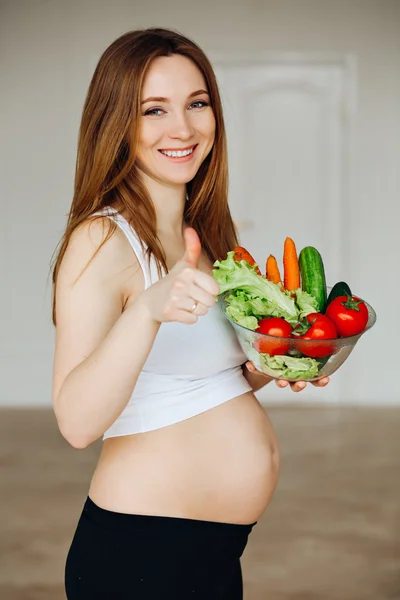 Pregnant Young Woman Cooking vegetables. Healthy Food - Vegetable Salad. Diet. Dieting Concept. Healthy Lifestyle. Cooking At Home. Prepare Food.