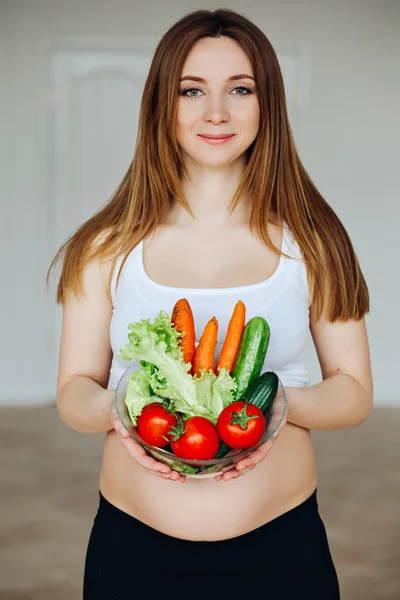Healthy nutrition and pregnancy. Close-up pregnant womans belly and vegetable salad. A beautiful pregnancy woman eating healthy food