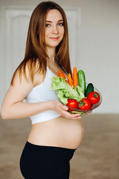 Healthy nutrition and pregnancy. Close-up pregnant womans belly and vegetable salad. A beautiful pregnancy woman eating healthy food