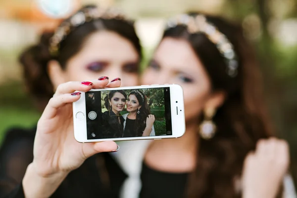 Girl friend doing a selfie. The girls at the party taking pictures of themselves on the phone. Women fashion stylish jewelry with precious stones.