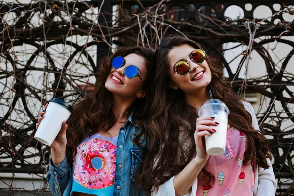 Summer lifestyle portrait of two hipster stylish women with fit sexy body, wearing denim outfit and vintage sunglasses. Girls friends going crazy, having fun, dancing, laughing and screaming.