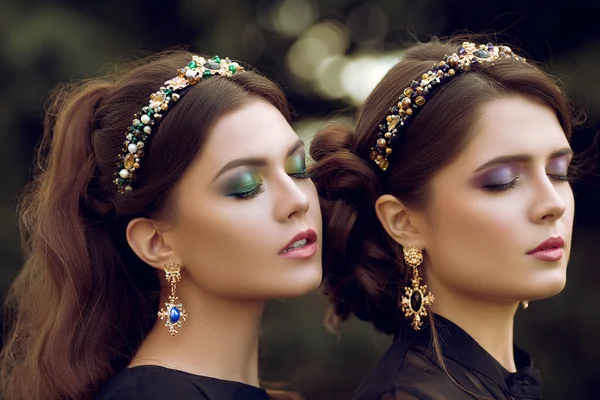 Two beautiful brunette women with a bright color makeup,jewelry,ring, earring, eyes closed. Close-up portrait of two girls with curly hair, hairstyles.