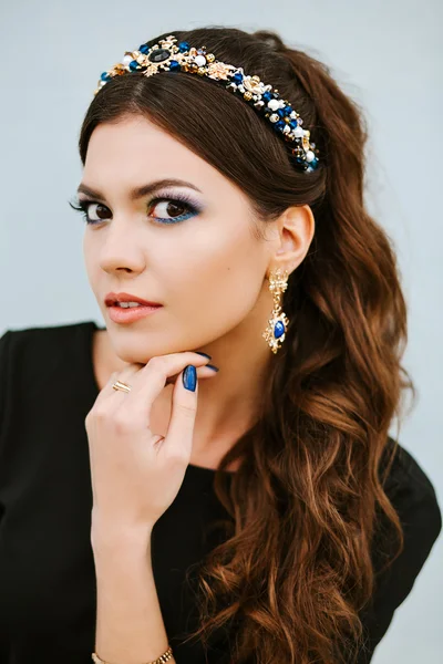 Street fashion portrait of beautiful woman with jewelry, jewelry with precious stones. Manicure and makeup in the same style blue, blue lacquer coating, blue jewelry.