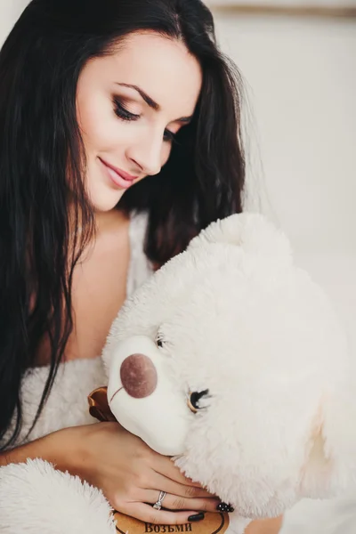 Beautiful young brunette girl with soft toy bear