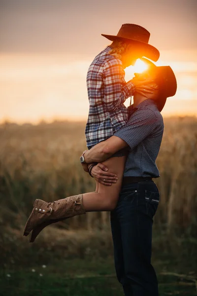 Couple of young adults in love by  at sunset. Man holding a woman his arms.