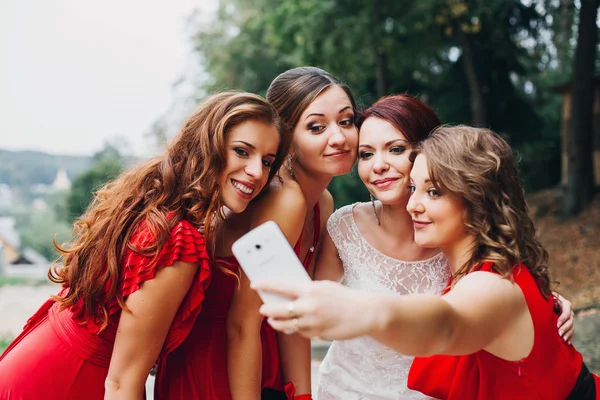 The bride and bridesmaids beautiful girls in red dresses doing selfie