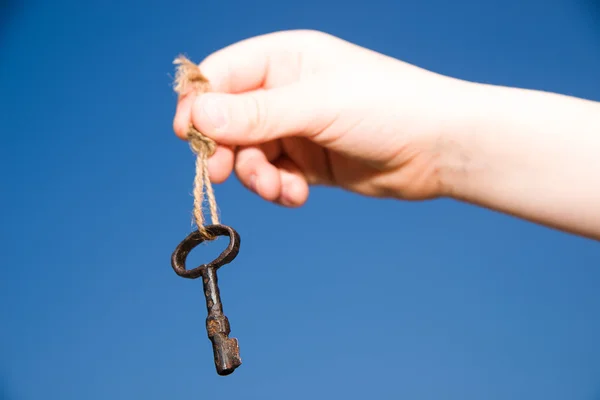 Child hand holding an old key on a string