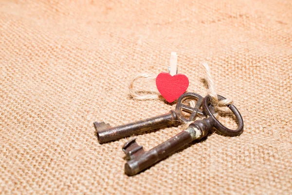 Two vintage key and a red heart on old cloth