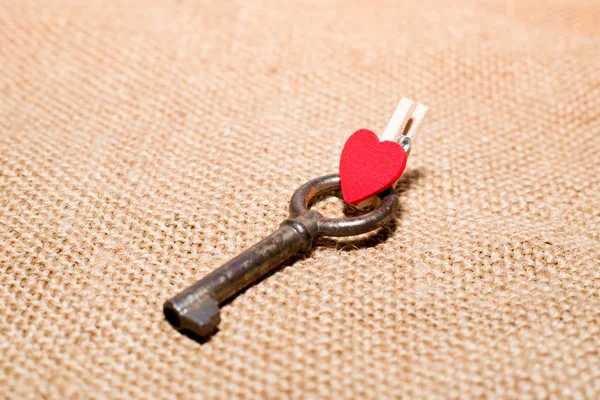 One Vintage key and a red heart on old cloth
