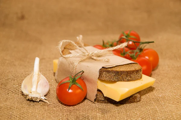 Sandwich with cheese wrapped in paper, cherry tomatoes and garli