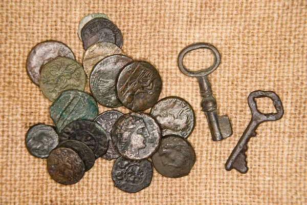 Ancient coins with portraits of kings and keys on the old clot