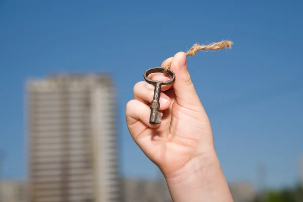 Child hand holding an old keys to the house against the sky