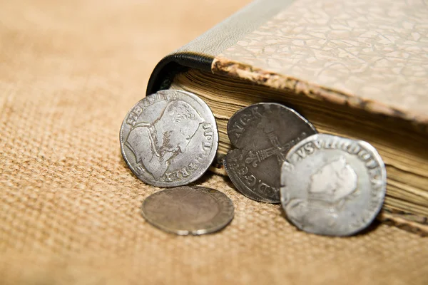 French old coin with a portrait of the King is on the book