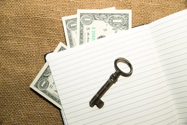 Opened notebook, key and money on the old tissue