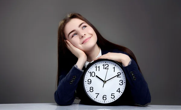 Portrait of beautiful young girl sitting with clock