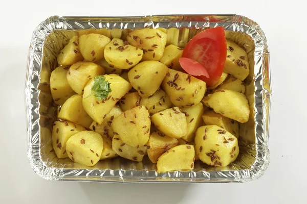 Indian dish fried potato with cumin in metal foil tray.