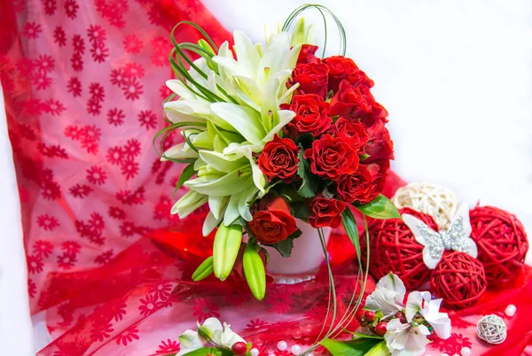 Wedding bouquet with lilies and red roses on a red background