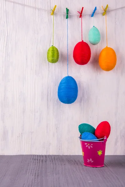 Easter knitted multi-colored eggs in a red bucket