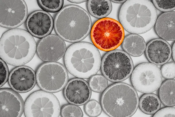 One red orange among black-and-white oranges