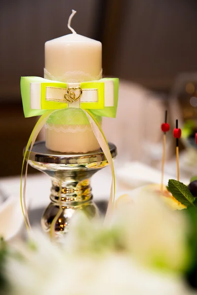 Wedding candle with a green bow on a support