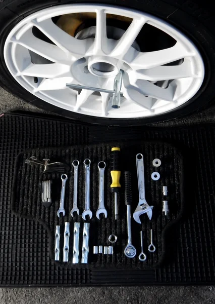 Set of wrenches and sockets for car disk mounting near car wheel at car workshop