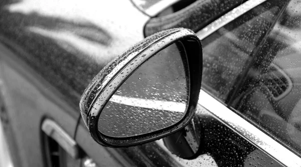 Rain drops on car mirror after water protection repellent coating
