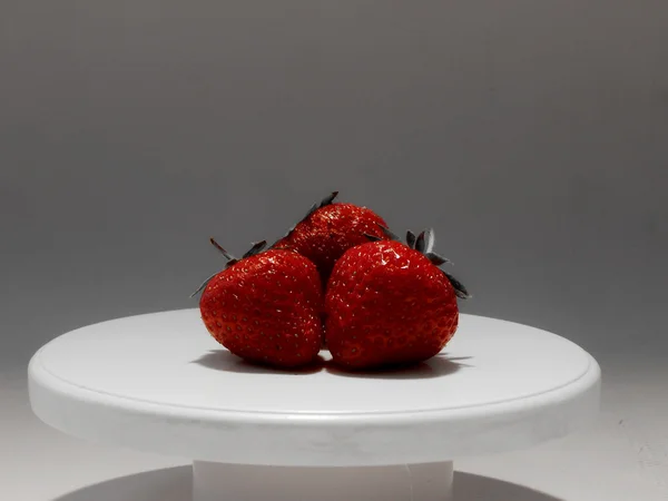 Red strawberries on white plate studio shot