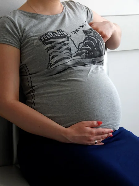 Pregnant woman sitting on couch at hospital and waiting gynecology appointment