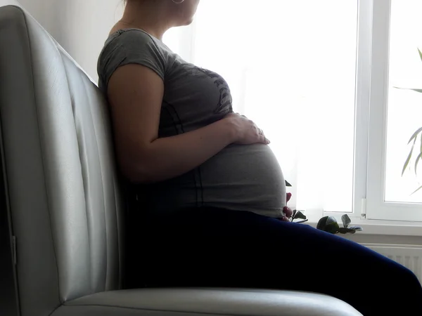 Pregnant woman sitting on couch at hospital and waiting gynecology appointment