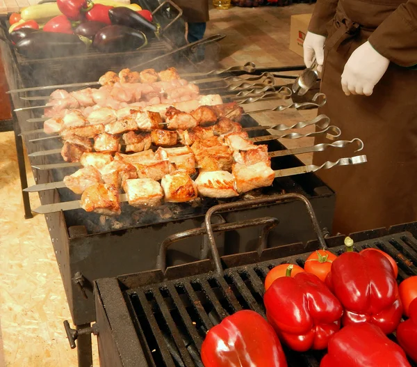 Male chef with white gloves fry the meat and red paprika on the grill
