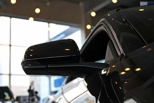 Mirror of black sport car in dealership car shop