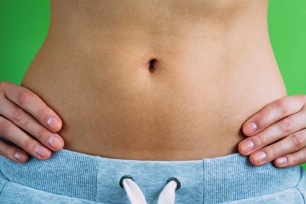 Young woman with bare belly holding hands on waist