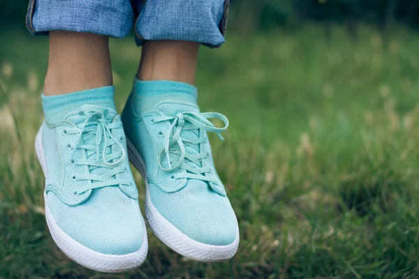 Female legs in jeans and sport shoe floating in the air above th