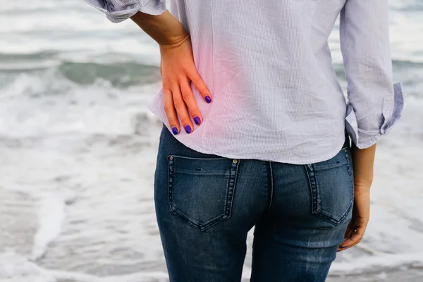 Woman in jeans and shirt standing on the shore and holding her l